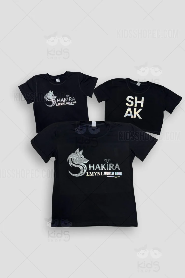 Colección de tres modelos de camisetas negras para niña inspiradas en el concierto de Shakira. Incluye opciones en corte clásico y blusas cortas (crop tops). Presentan estampados de alta fijación con efecto metalizado plateado/holográfico, mostrando el logo LMYNL, la silueta de Shakira, el rostro de loba y el diseño del billete de 100 dólares. Confección de Kids Shop EC en Quito.