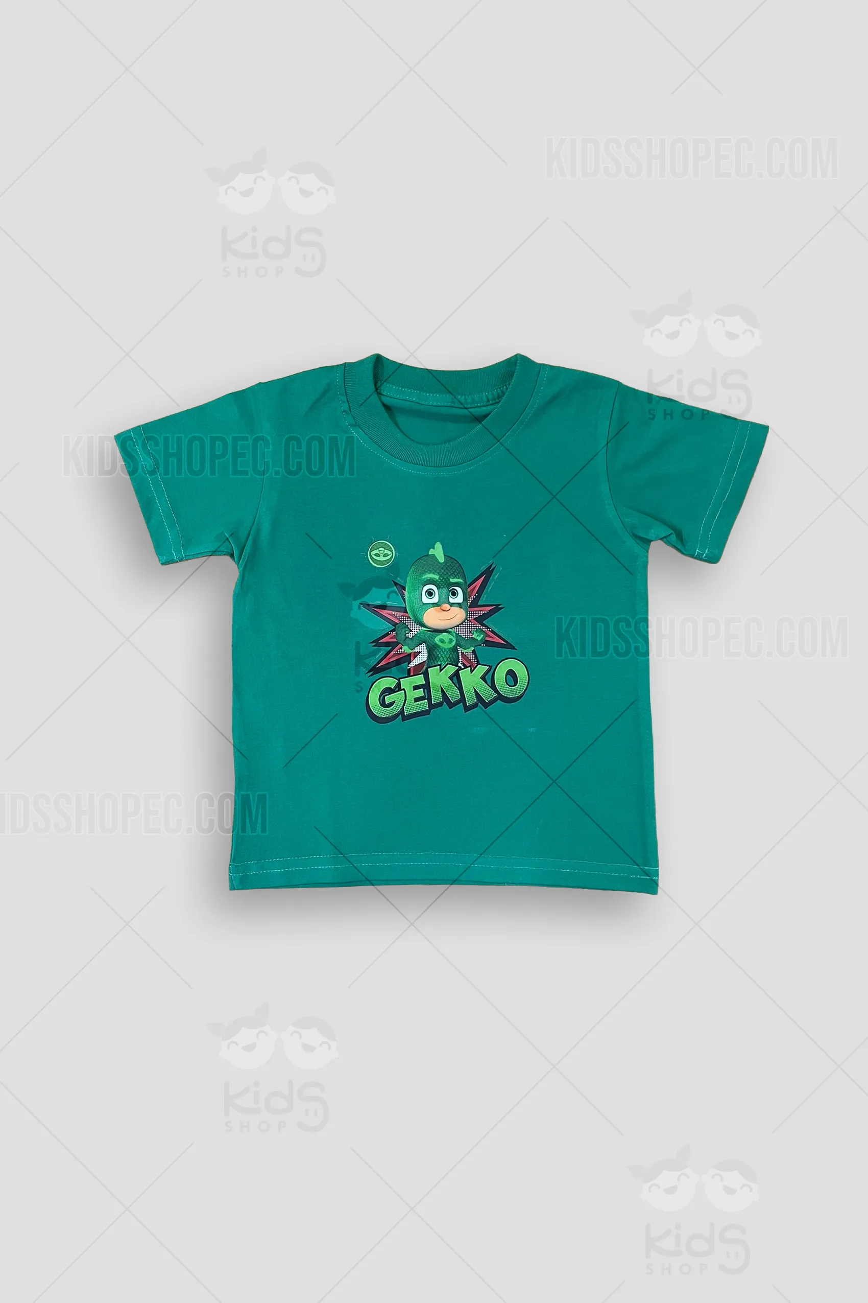 Fotografía frontal, detalle y trasera de una camiseta infantil de manga corta y cuello redondo en color verde sólido. En el pecho presenta un vibrante estampado a todo color del personaje animado "Gekko", con un fondo de explosión estilo cómic en rojo y negro, y la palabra "GEKKO" en letras verdes tridimensionales. La espalda es completamente lisa en color verde. Se exhibe sobre un fondo gris neutro con marcas de agua de Kids Shop EC.