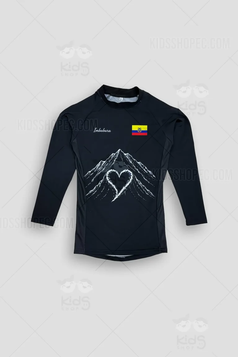 Fotografías de una camiseta deportiva de manga larga color negro, de corte ajustado tipo ciclismo o rashguard. En la parte frontal presenta la palabra 'Imbabura', la bandera de Ecuador y una ilustración blanca de montañas formando un corazón en el centro. En la parte trasera, lleva estampado el nombre personalizado 'HAZIELITOM' sobre una ilustración lineal blanca muy detallada de una máscara tradicional andina de Aya Huma (Diablo Huma). La prenda se muestra sobre un fondo gris claro con marcas de agua de Kids Shop EC.
