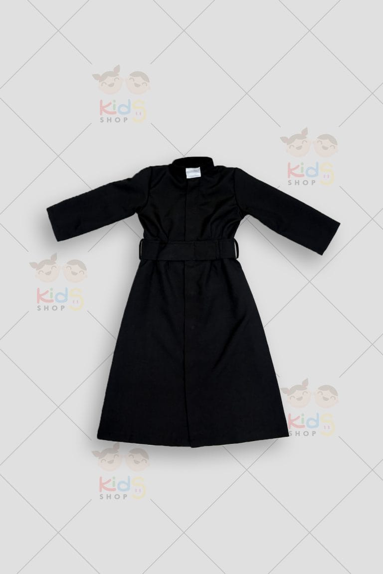 Fotografía de un disfraz infantil de hábito religioso de color negro. Consiste en una túnica larga de manga larga con un cinturón ancho de tela a juego. En el cuello alto y cerrado destaca el clásico alzacuellos o cuello clerical de color blanco (cuello romano). La prenda de corte recto y sobrio se muestra extendida plana sobre un fondo gris neutro con marcas de agua de Kids Shop EC.