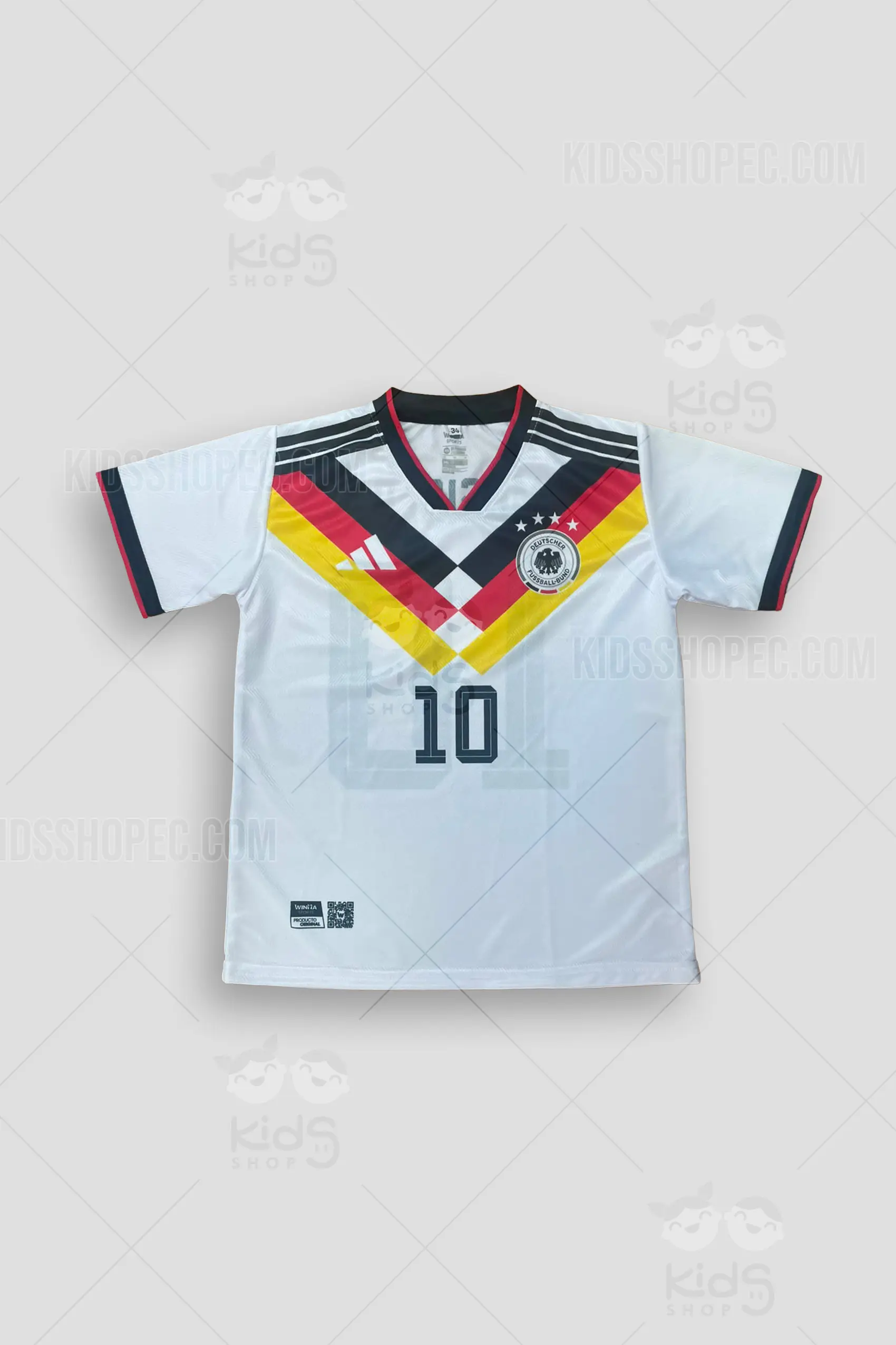 Fotografías de estudio de una camiseta de fútbol de manga corta, color blanco con un diseño en el pecho en forma de "V" con gruesas franjas en negro, rojo y amarillo. Presenta cuello en 'V' y puños con finos ribetes tricolores. En el pecho izquierdo lleva estampado un escudo circular con un águila negra y cuatro estrellas, además de un logotipo deportivo y el número 10 oscuro en el centro. En la espalda destaca el nombre 'MUSIALA' sobre un gran número 10 con un diseño de líneas que simula efecto de sombra. Vistas frontales, traseras y detalles de primer plano sobre un fondo gris claro.