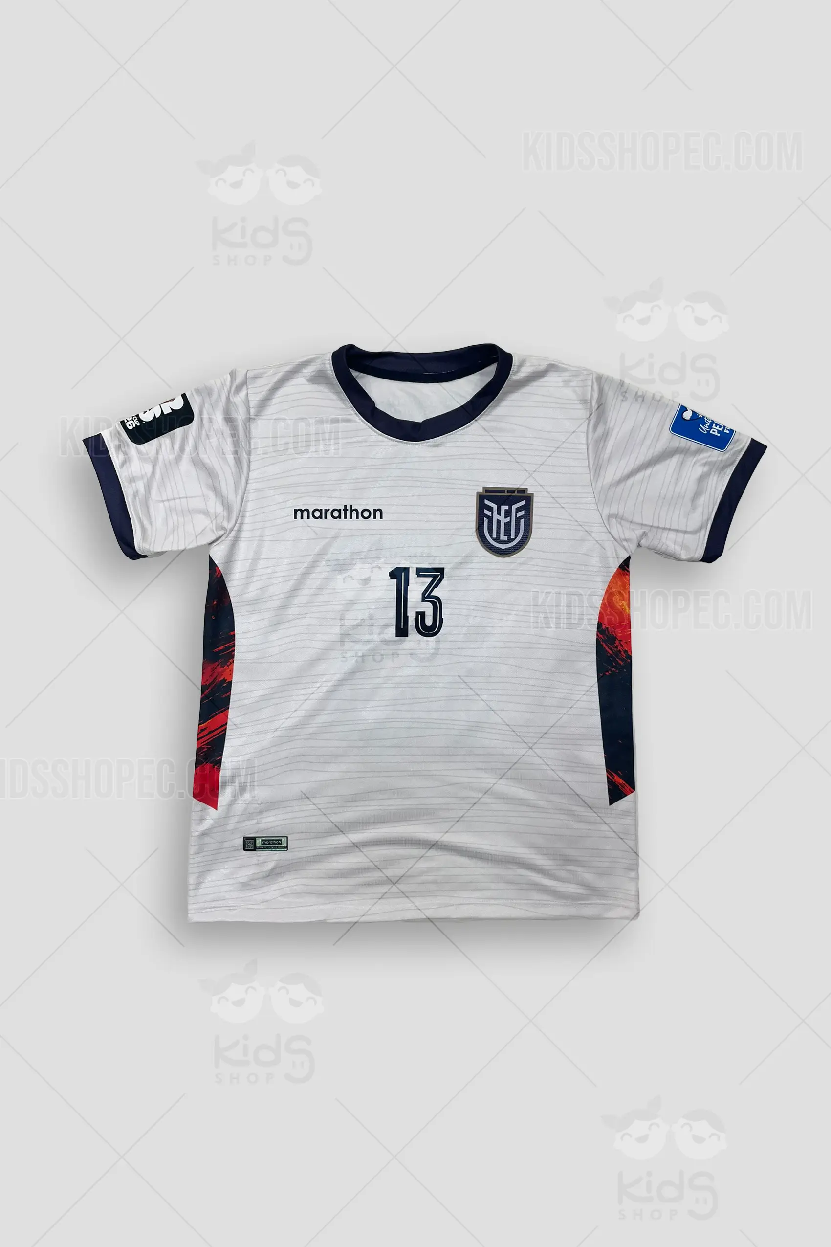 Fotografías de estudio de una camiseta deportiva de fútbol de manga corta, con base de color blanco texturizada con finas líneas horizontales grises. Presenta cuello redondo y puños en color azul marino, y paneles laterales con gráficos abstractos en rojo, azul y amarillo. En el pecho izquierdo lleva estampado un escudo representativo deportivo en azul marino y gris, junto al número 13 frontal. En la espalda destaca el texto 'E. VALENCIA' impreso sobre un número 13 grande en azul marino, además de una frase pequeña en la parte superior trasera. Fondo gris claro.