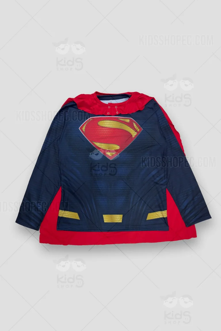 Fotografías de estudio en formato flat lay de un buzo o camiseta de manga larga inspirado en Superman. La prenda presenta un color azul marino oscuro con un sutil patrón de textura y líneas geométricas más oscuras que simulan musculatura o armadura. En el centro del pecho luce el clásico escudo de la "S" en rojo y dorado texturizado. En la parte inferior tiene detalles dorados impresos a modo de cinturón. Se acompaña de una capa roja removible con ojales de fijación en el cuello y el mismo escudo impreso en la espalda.