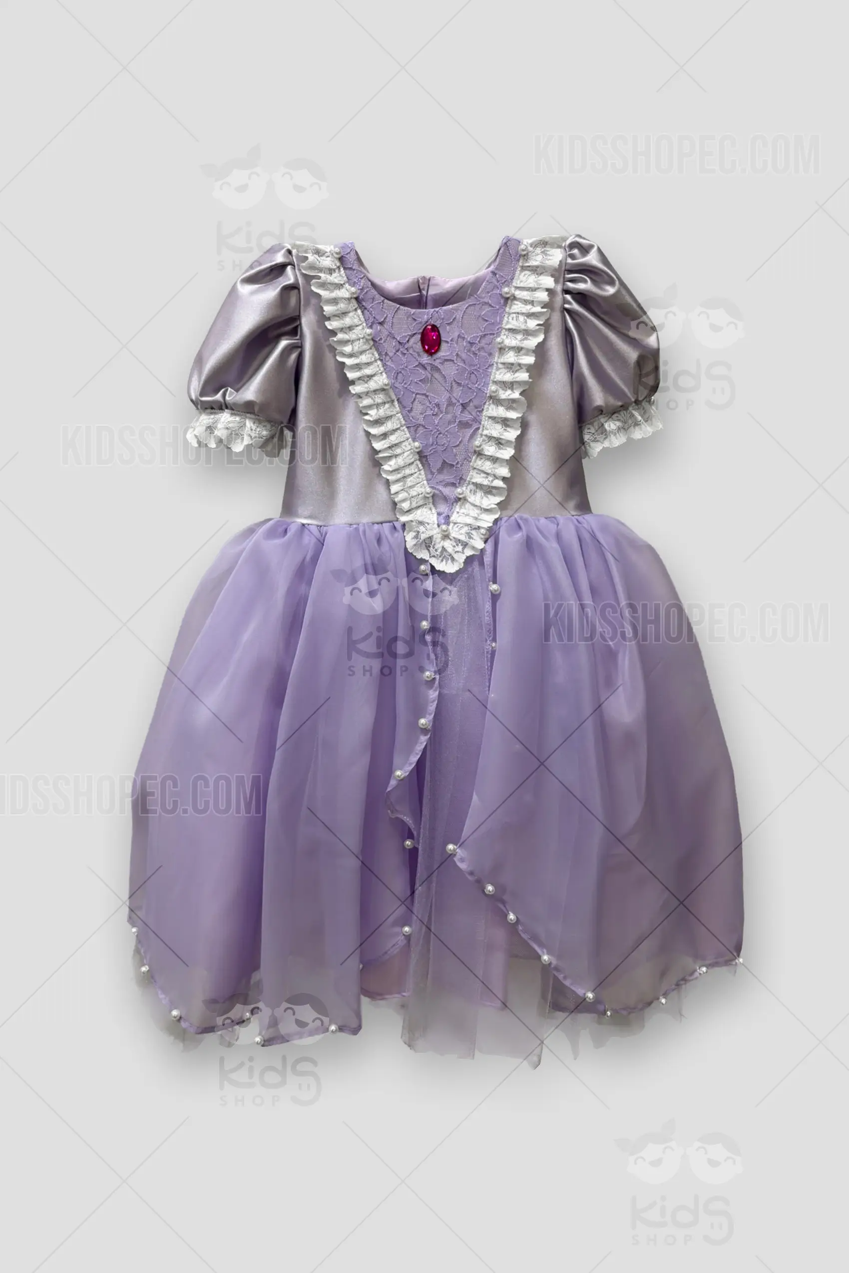 Fotografías de estudio en formato flat lay de un vestido infantil de estilo princesa. El corpiño es de satén plateado con mangas cortas abullonadas rematadas en encaje blanco. El pecho presenta un panel en "V" de encaje morado, bordeado con encaje blanco con volantes, perlas incrustadas y un broche de joya roja en el centro. La falda es de color lila con una capa superpuesta de tul transparente, adornada con perlas blancas a lo largo del dobladillo y la abertura frontal. La espalda cuenta con un cierre invisible y un gran lazo de satén plateado en la cintura.