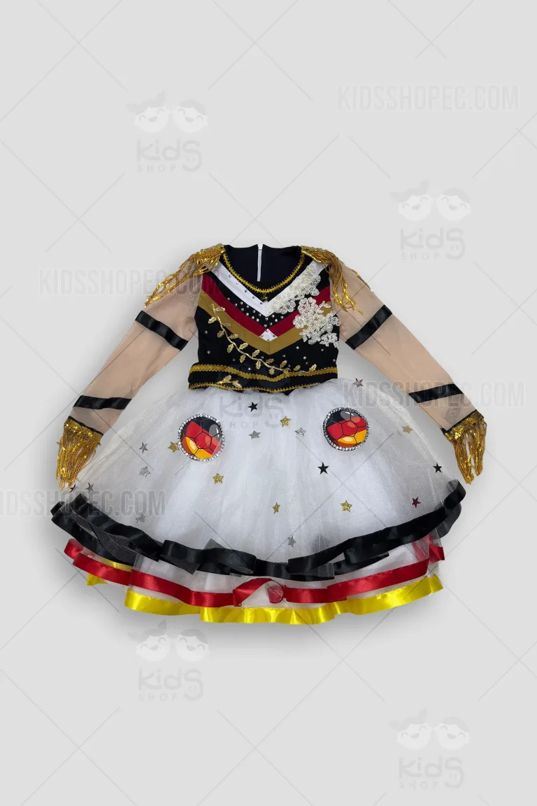 Fotografías de estudio en formato flat lay de un vestido infantil de fantasía. La parte superior presenta un corpiño negro con franjas en V (blanco, rojo y dorado) adornadas con pedrería brillante, apliques de encaje floral blanco y charreteras de flecos dorados en los hombros. Las mangas largas son de malla traslúcida beige con cintas negras entrelazadas y puños con flecos dorados. La falda voluminosa es de tul blanco, decorada con estrellas brillantes esparcidas y dos grandes apliques circulares sublimados con diseño de balón de fútbol en los colores de Alemania. El dobladillo inferior cuenta con un acabado de cintas en negro, rojo y amarillo.